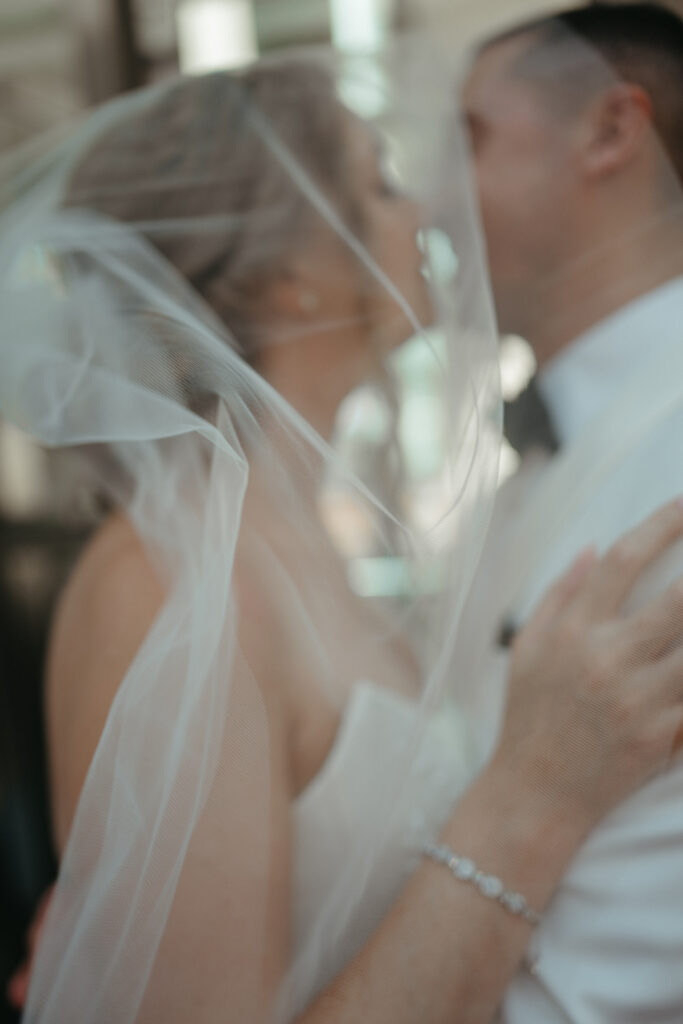 close up of a bride and groom kissing under a veil