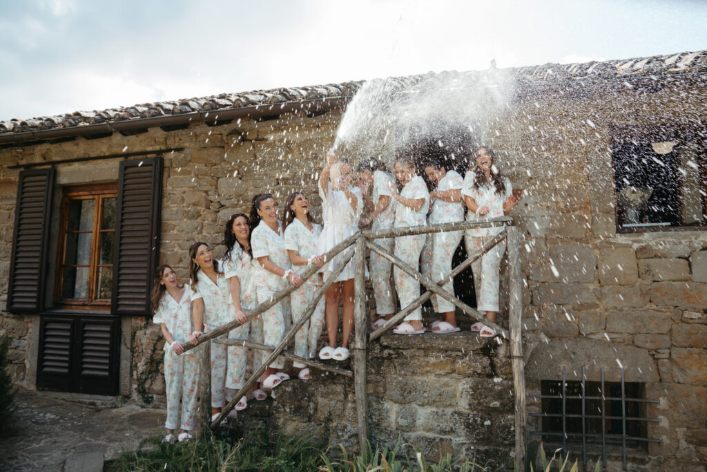 bride with bridesmaids spraying champagne at castello di ristonchi wedding