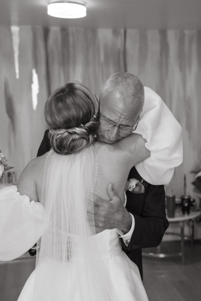 Bride hugs father after first look. 