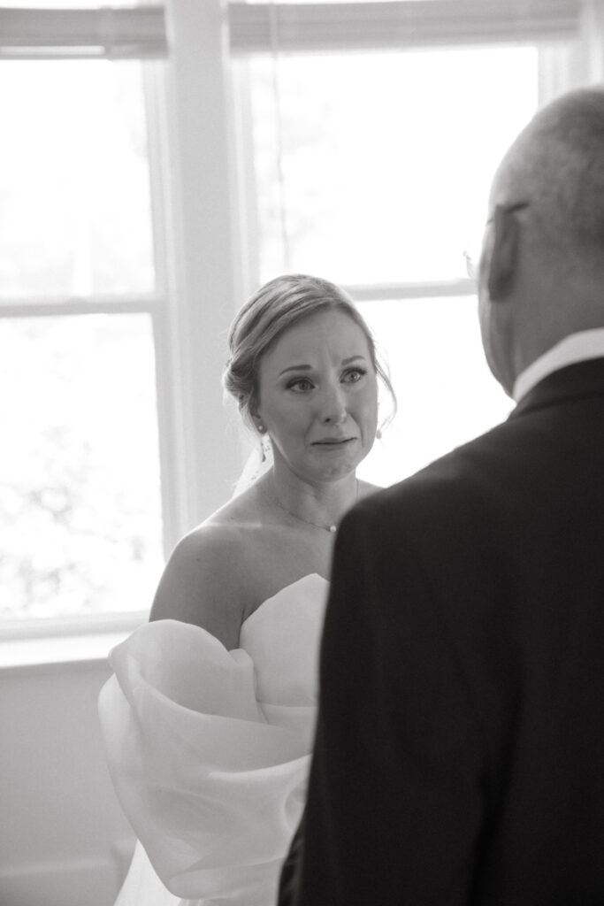 Bride, emotional, stands in front of father after first look at her wedding. 