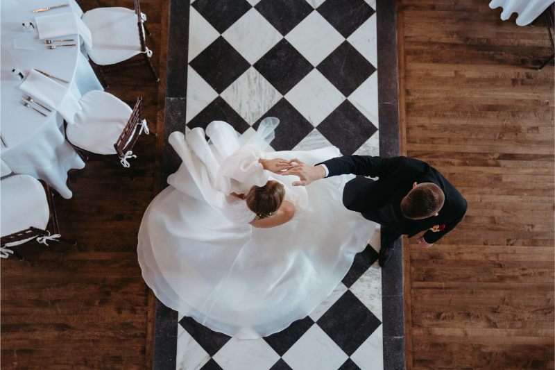 Groom spins bride on a checkered aisle.