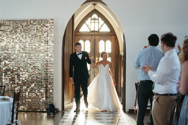 Bride and groom walk into reception area after their wedding ceremony. 