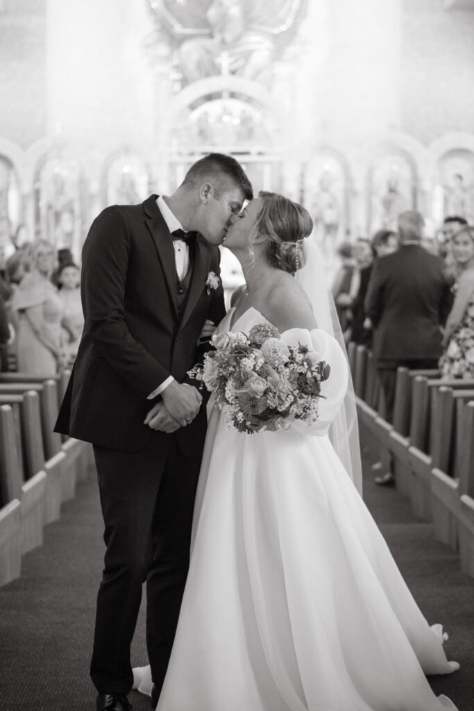 black and white photo of bride and groom sharing a kiss after st nicholas wedding ceremony