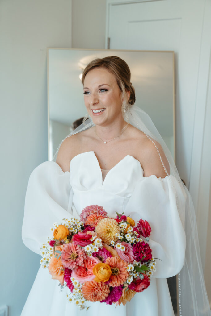 bride in dress holding bouquet of pink, white, and yellow florals