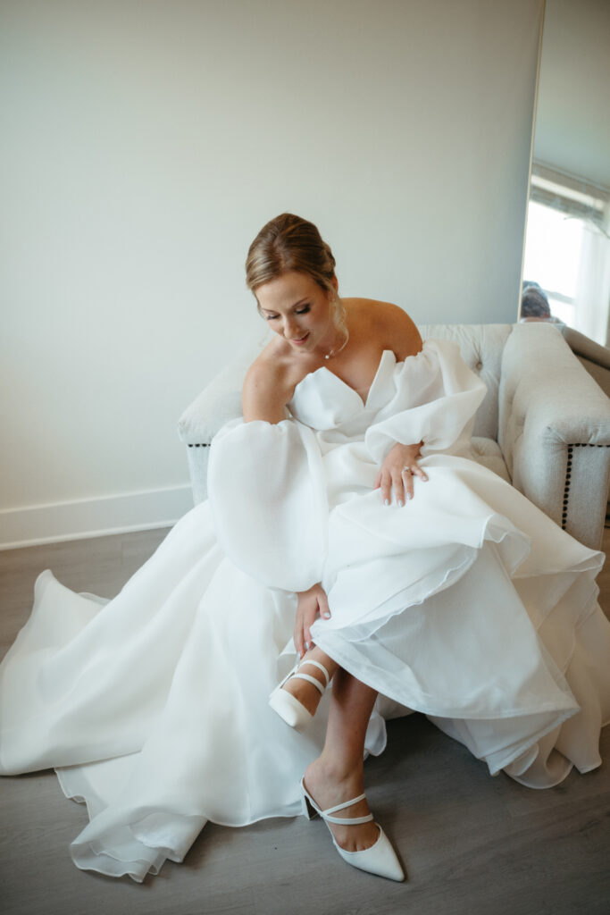 bride sitting down adjusting bridal shoe