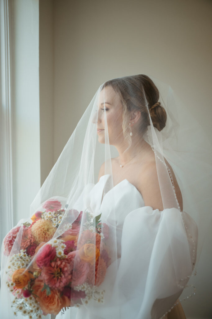 bride with wedding dress and veil on looking out the window