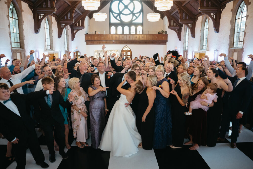 bride and groom share a kiss while wedding guests celebrate around them