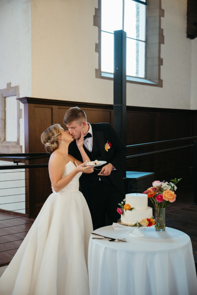 bride and groom share a kiss during their cake cutting ceremony at their reception at the palomar cincinnati