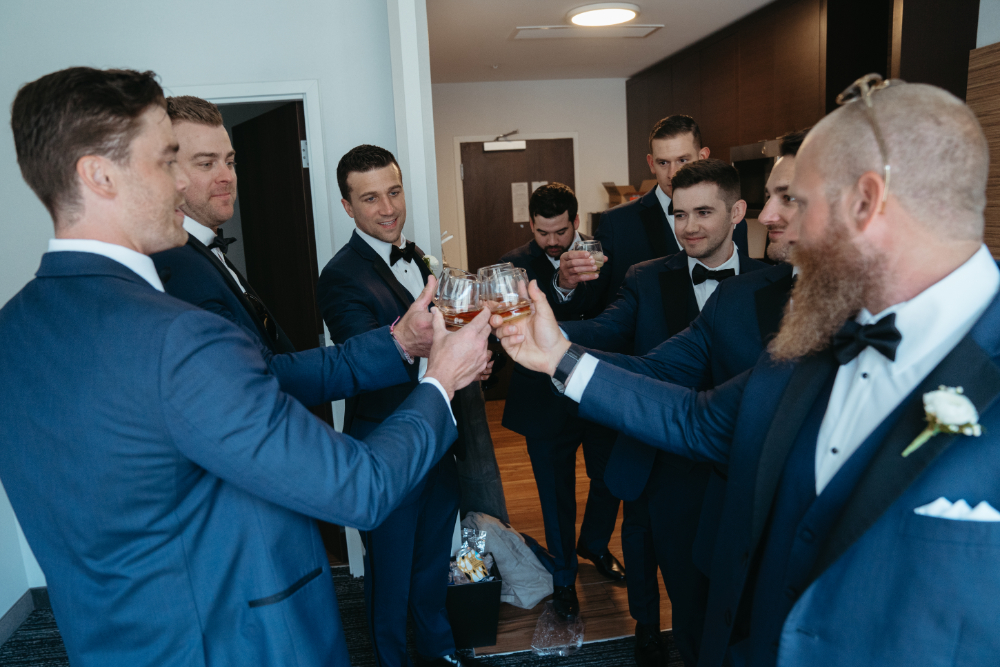 Groomsmen and groom toasting with drinks.