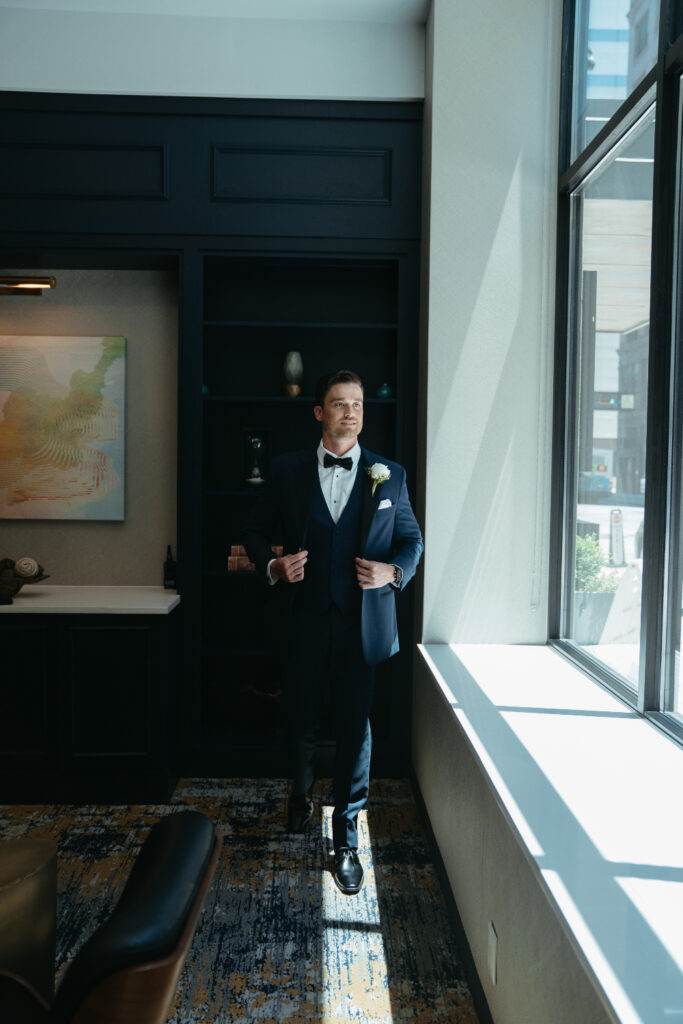 Groom standing by a window in a modern lounge.