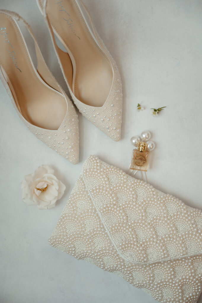 Pearl-embellished wedding shoes, clutch, and perfume.