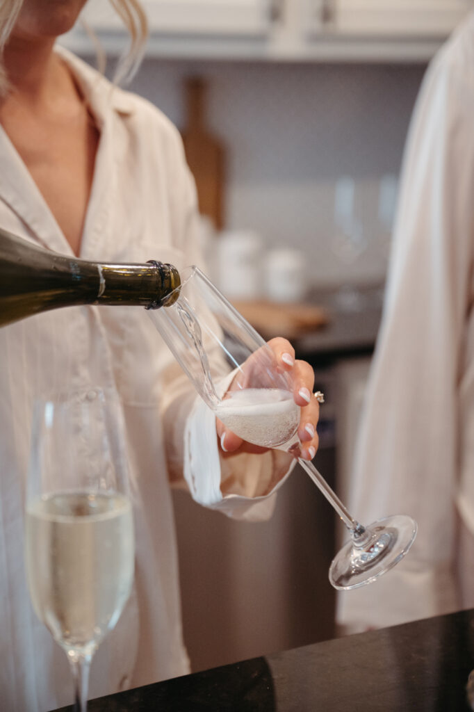 Champagne being poured into a flute by bride.