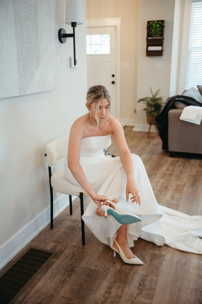 Bride putting on pearl-studded heels.