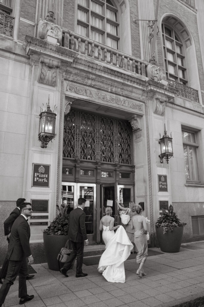 Bride, groom, and wedding party enter The Cincinnati Club.
