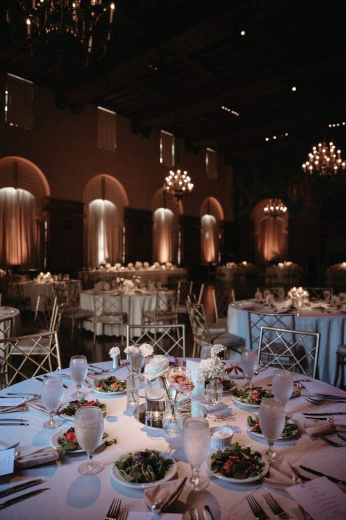 Candlelit tables and gold chairs under chandeliers.
