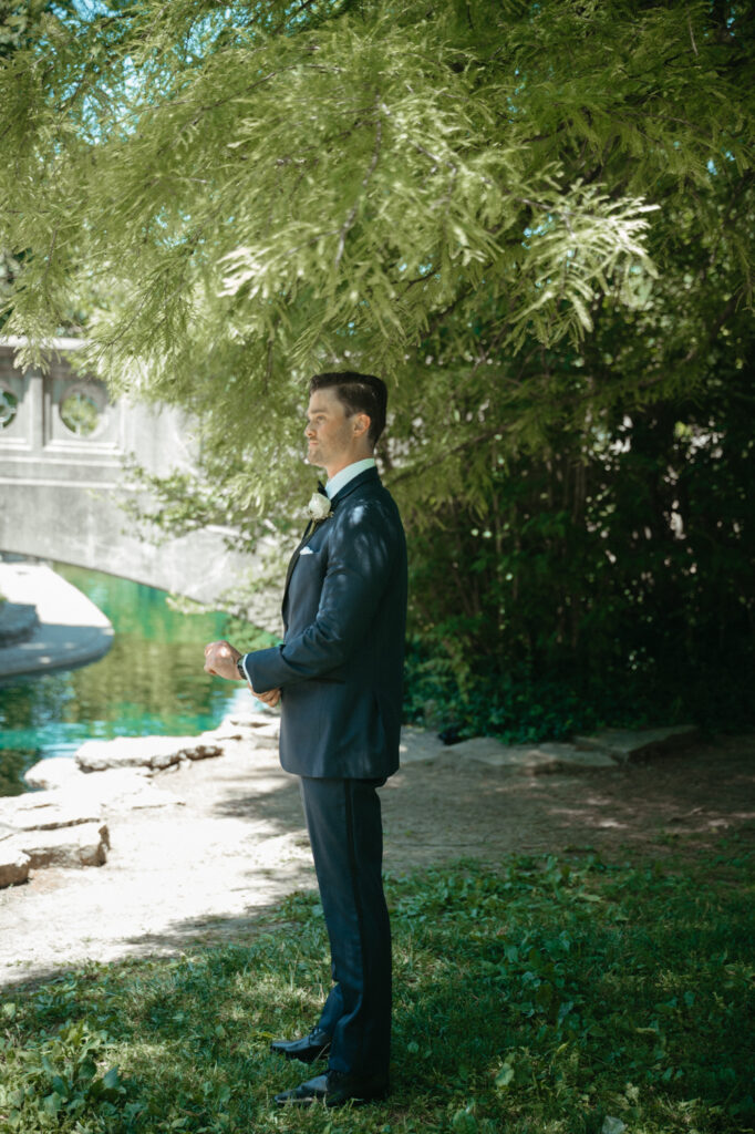 Groom waiting under a tree for the first look.
