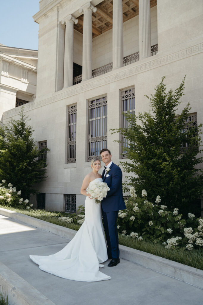 Bride and groom posing in front of a neoclassical building.






