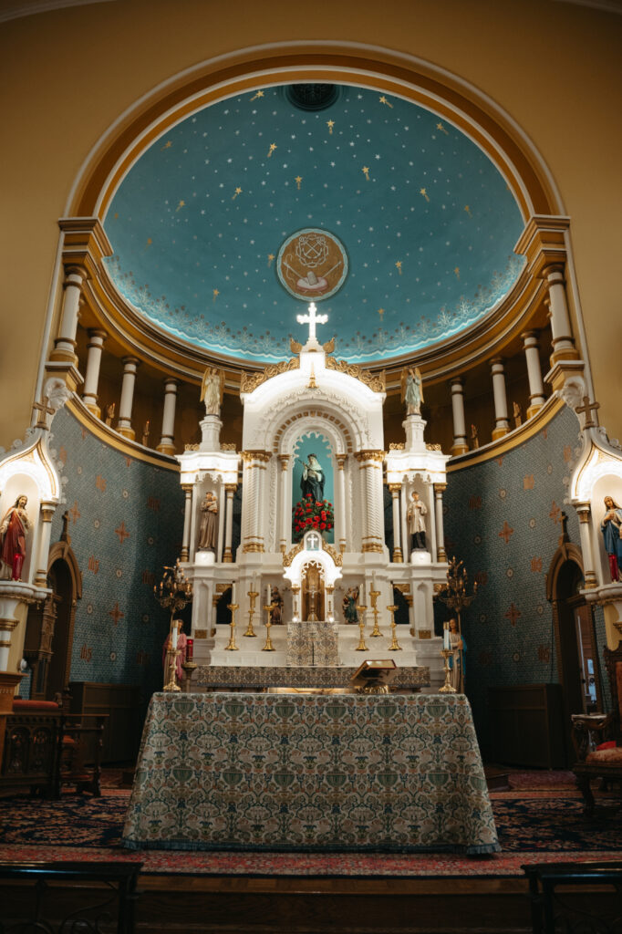 Ornate church altar at St. Rose Catholic Church with statues, candles, and a blue dome ceiling with gold stars.
