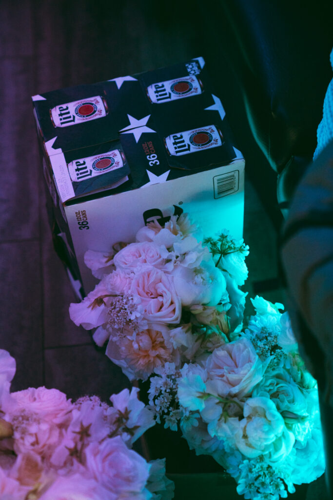 Case of beer next to bridal bouquets inside the party bus.






