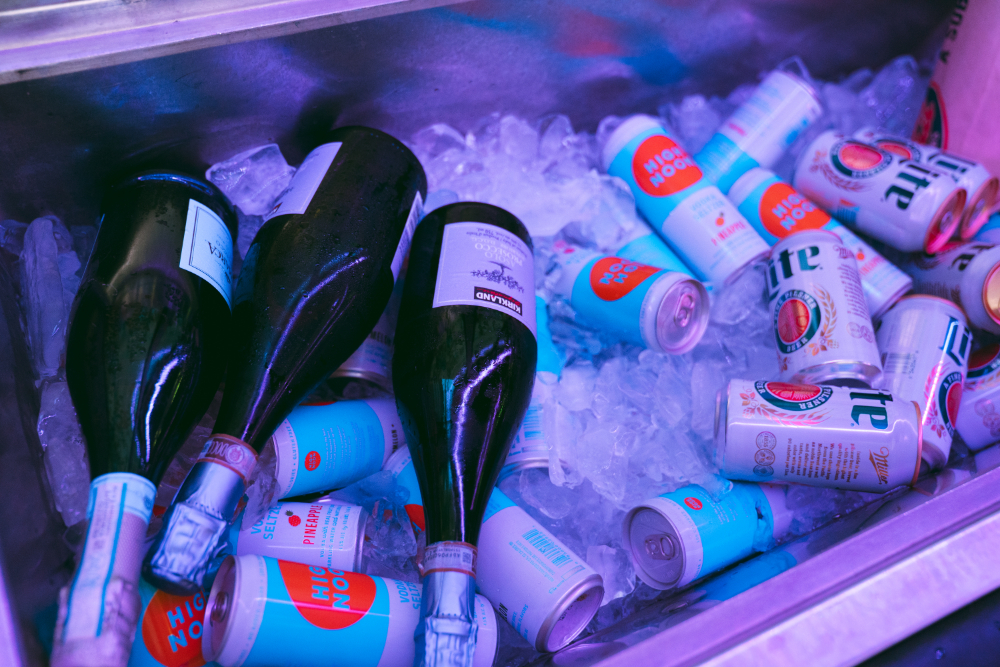 Bottles of champagne and cans of beer and seltzer on ice.
