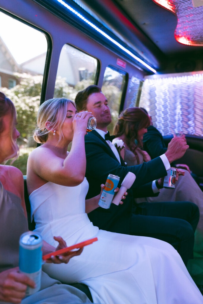 Bride drinking from a glass in the party bus.
