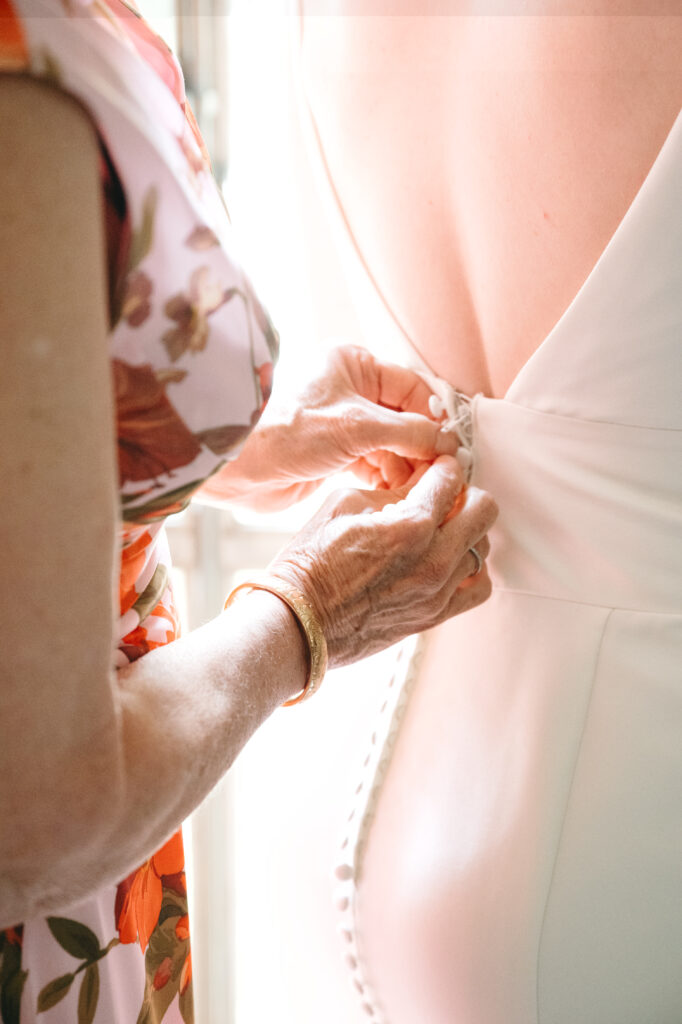 real-wedding-feature close up photo of the mother of the bride doing up the clasps on the back of the brides dress