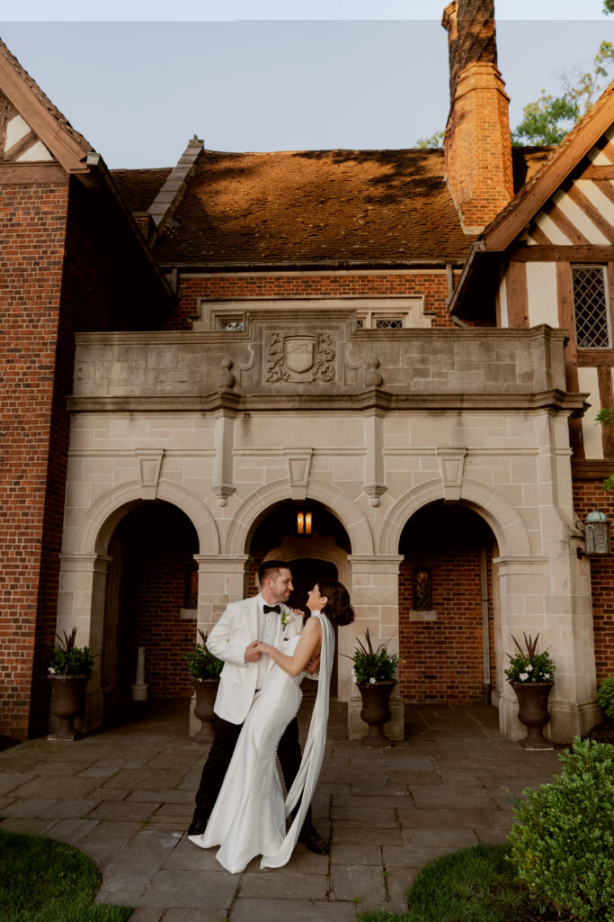 The couple shares a romantic dance in front of Pinecroft’s grand arched entrance at golden hour.
