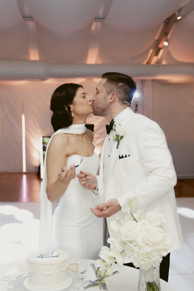 The couple shares a sweet kiss after cutting their cake at Pinecroft at Crosley Estate.