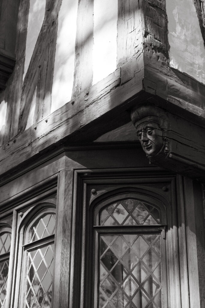 Black-and-white detail of Pinecroft at Crosley Estate’s leaded windows and carved architectural face ornament.