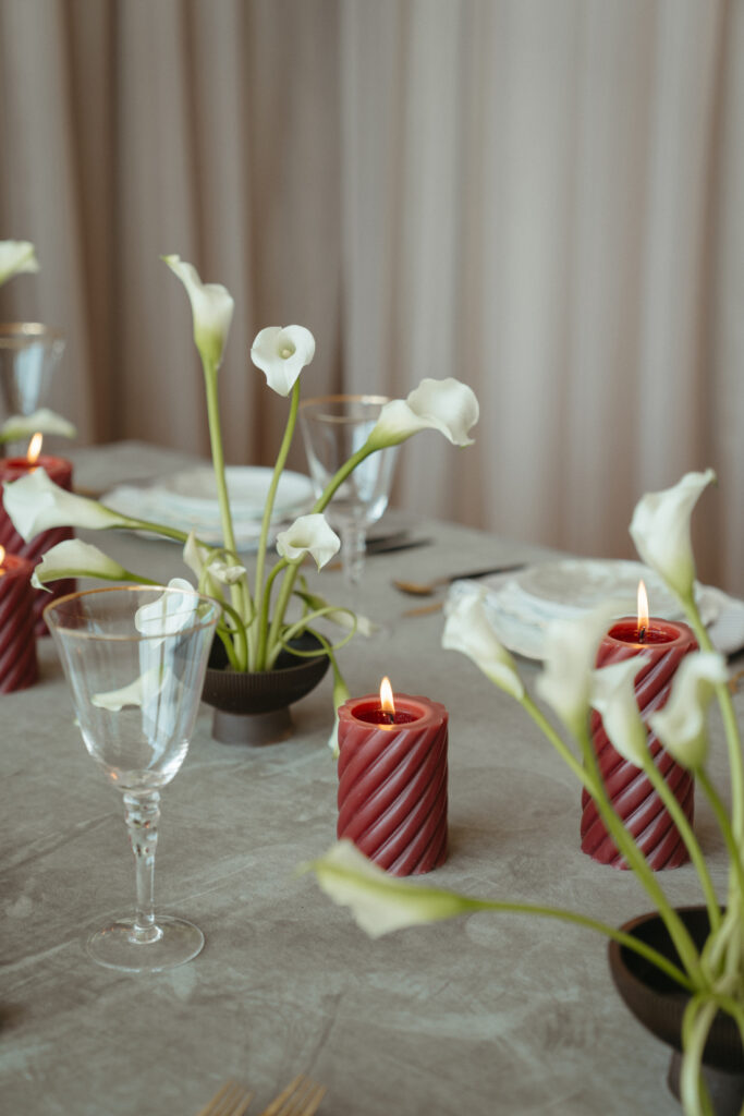 wedding-color-palette Elegant tablescape with red spiral candles and white calla lilies in modern black vases.