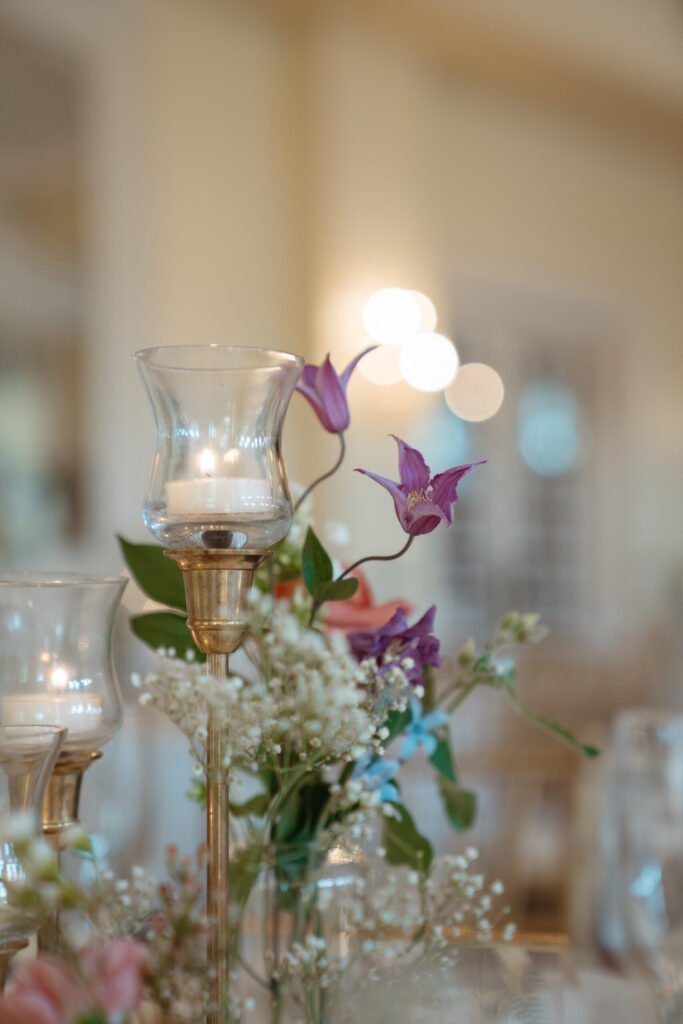 wedding-color-palette Delicate purple blooms and soft white baby's breath surround glowing candles in elegant glass holders.