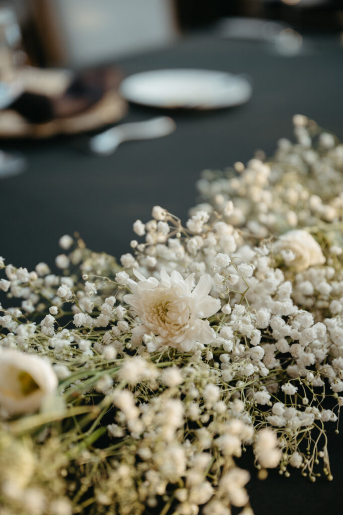 wedding-color-palette Soft white baby's breath and delicate blooms create an airy, romantic floral arrangement on black linen.