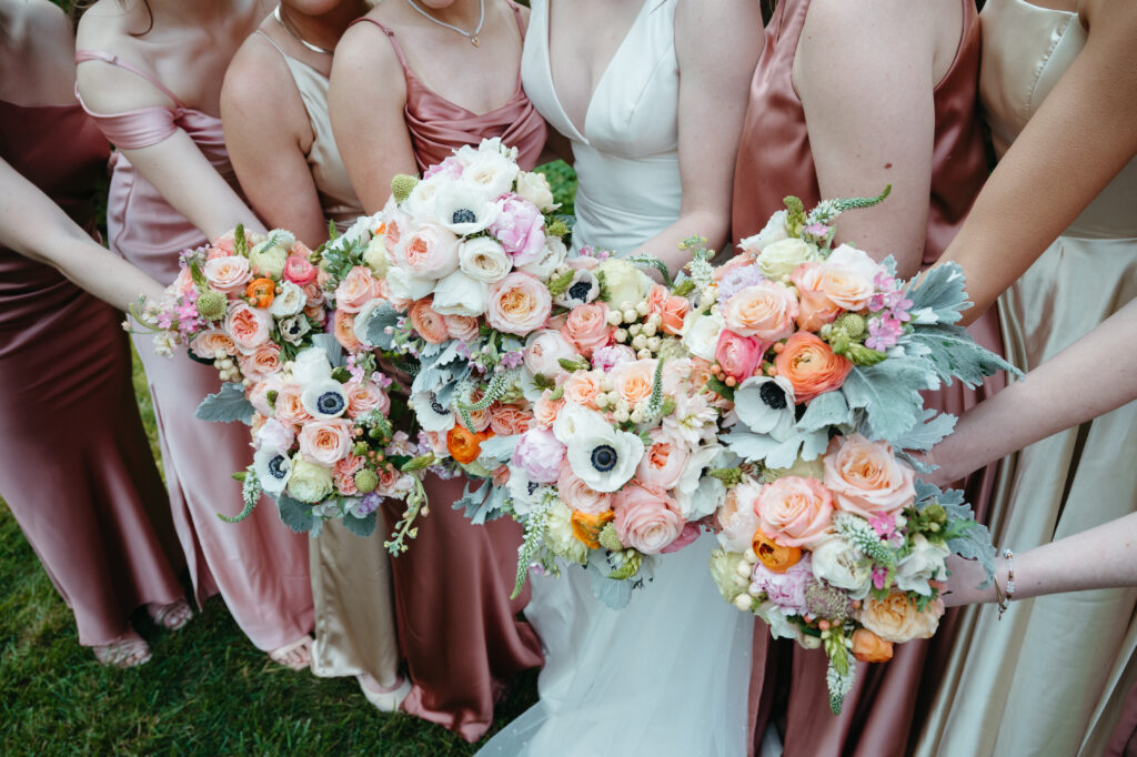 wedding-color-palette Romantic wedding color palette with soft peach, blush, and ivory flowers held by bridesmaids.