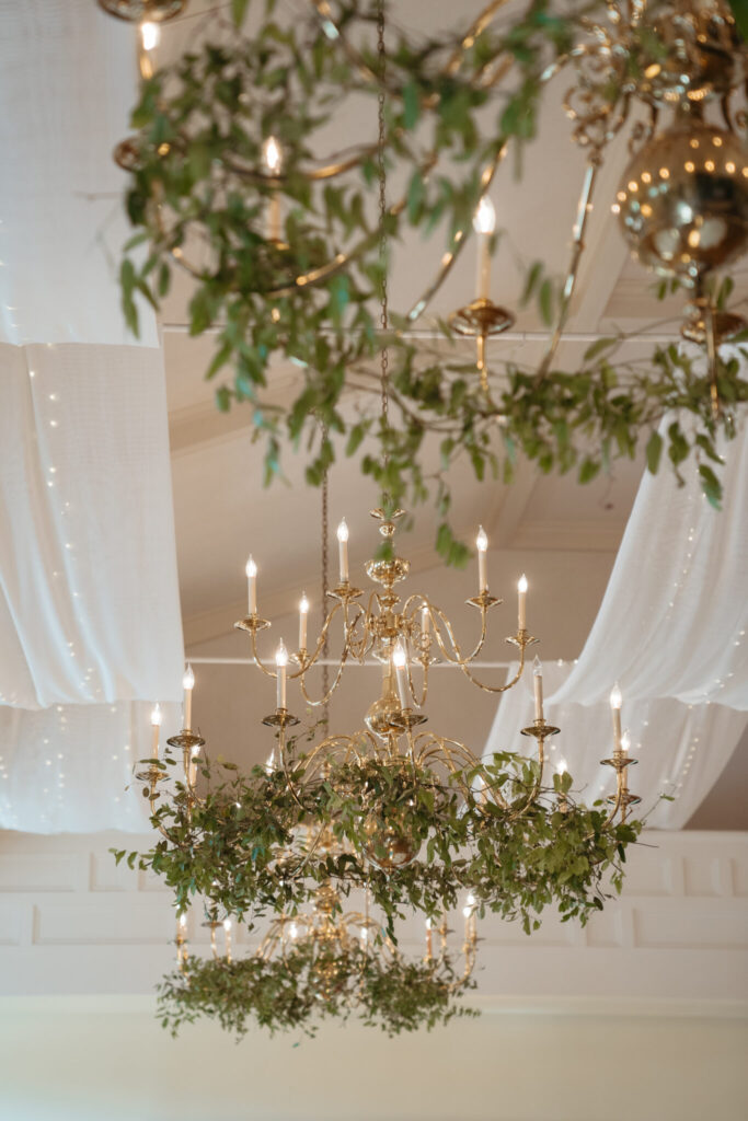 wedding-color-palette Elegant wedding color palette complemented by gold chandeliers adorned with lush greenery and soft drapery.
2/2