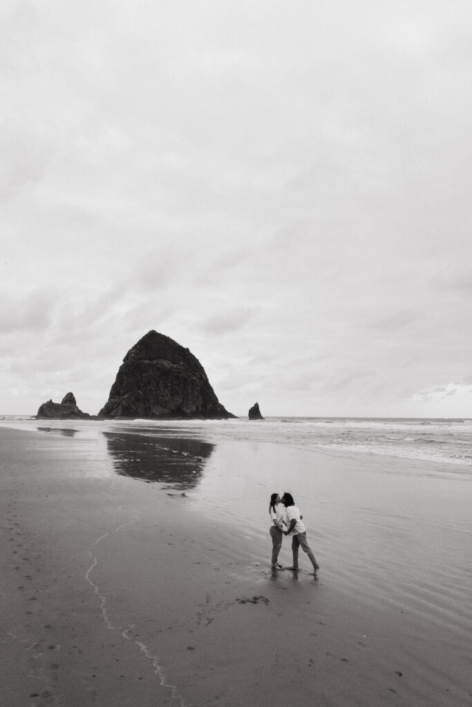 Black and white photo of couple kissing on the beach during their Oregon Coast elopement near Haystack Rock.