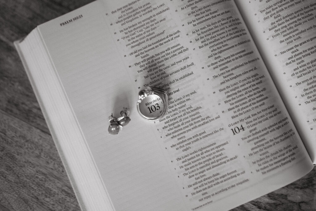 Open Bible displaying Psalm 103 with a locket and earrings placed on the page.