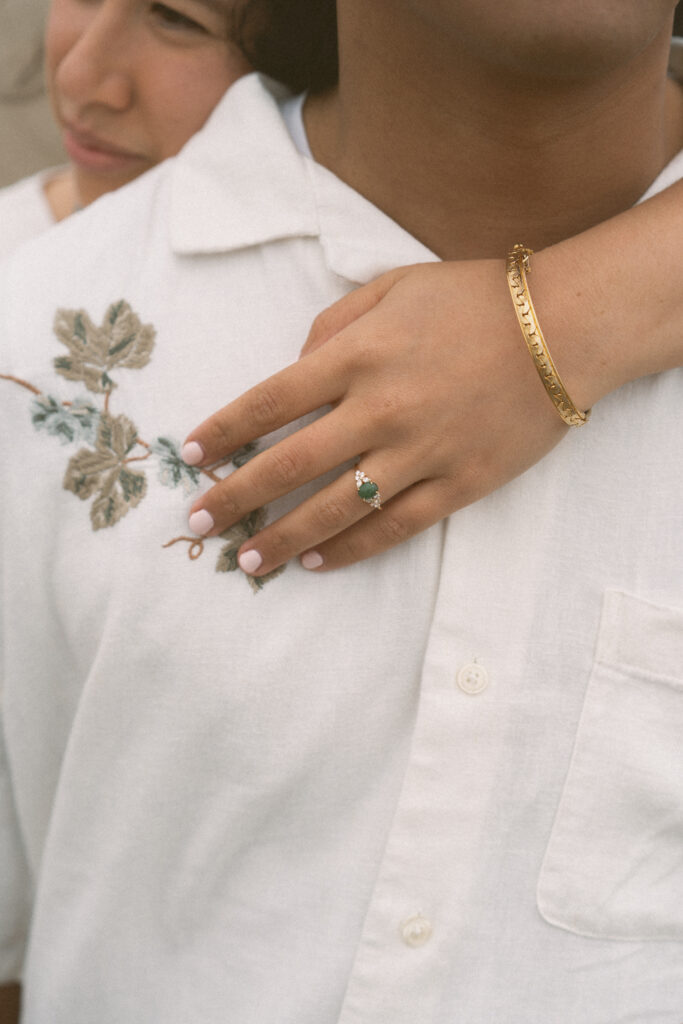 Close-up of engagement ring and gold bracelet during an Oregon Coast elopement, with soft natural light.