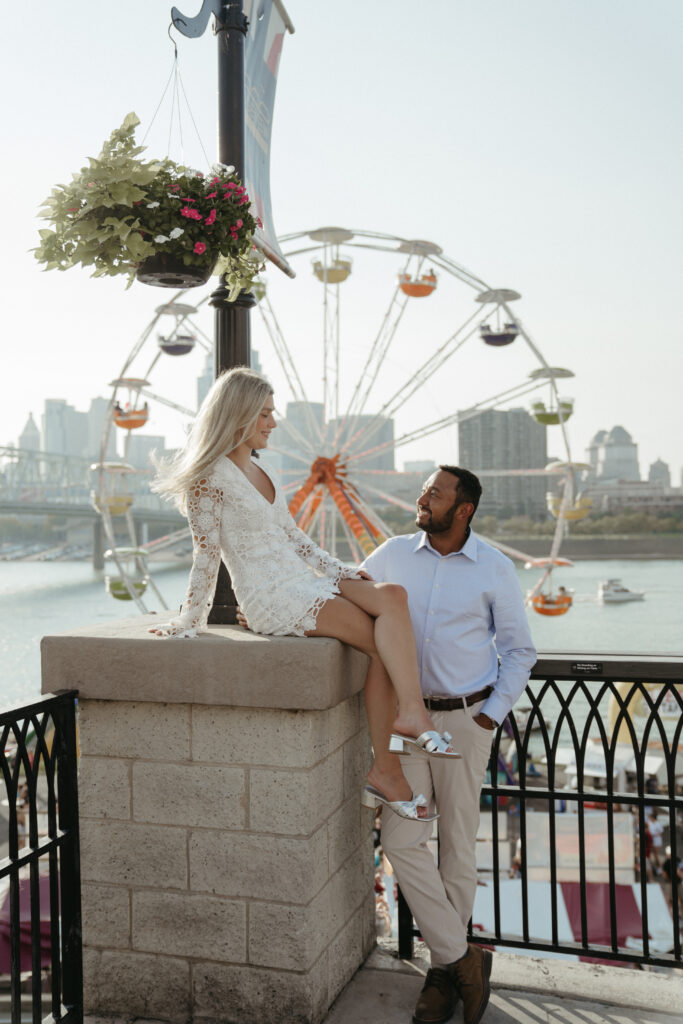 engagement-photo-tips Couple posing near the Ferris wheel at Newport on the Levee during their Cincinnati engagement session, captured as part of unique engagement photo tips.
