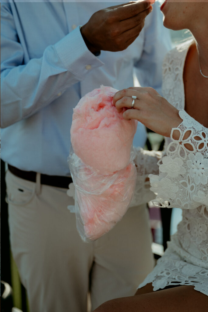engagement-photo-tips Close-up of a couple sharing cotton candy during their Cincinnati engagement session, with a focus on the engagement ring and creative engagement photo tips.