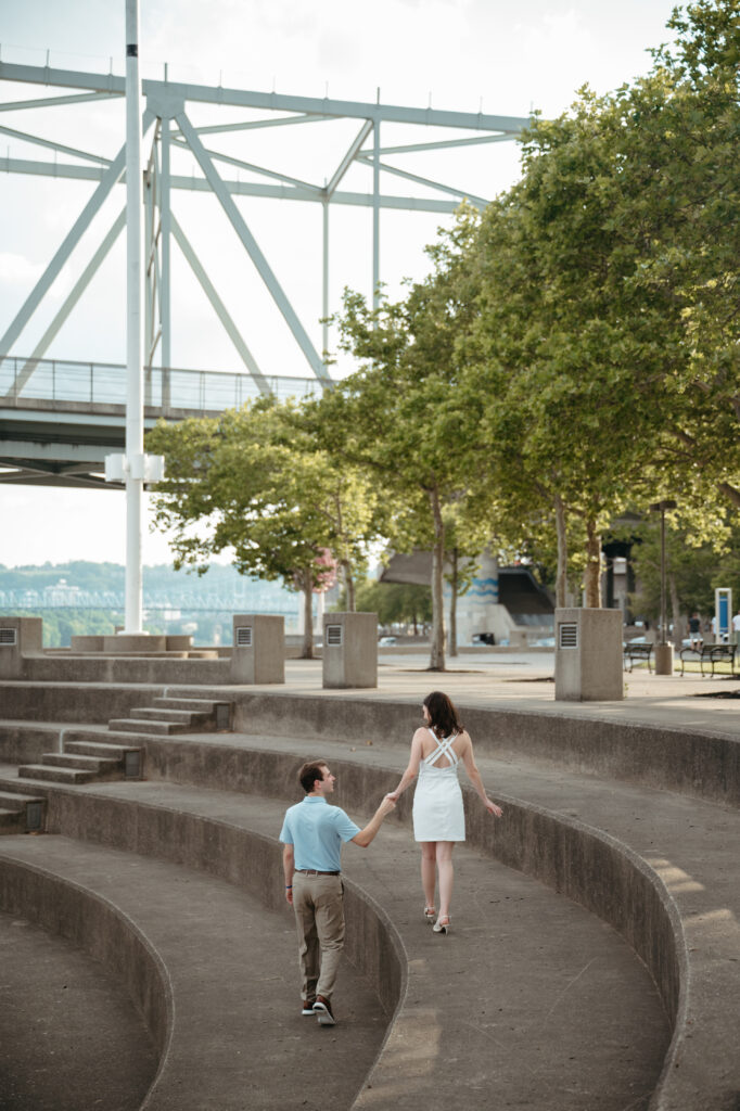 engagement-photo-tips Couple holding hands and walking through the amphitheater steps at Sawyer Point during their Cincinnati engagement session, captured as part of creative engagement photo tips.