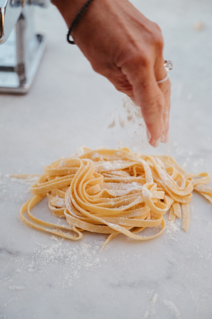 Close-up of fresh pasta being made by hand with a traditional machine — a meaningful cultural experience for couples getting married in Italy.