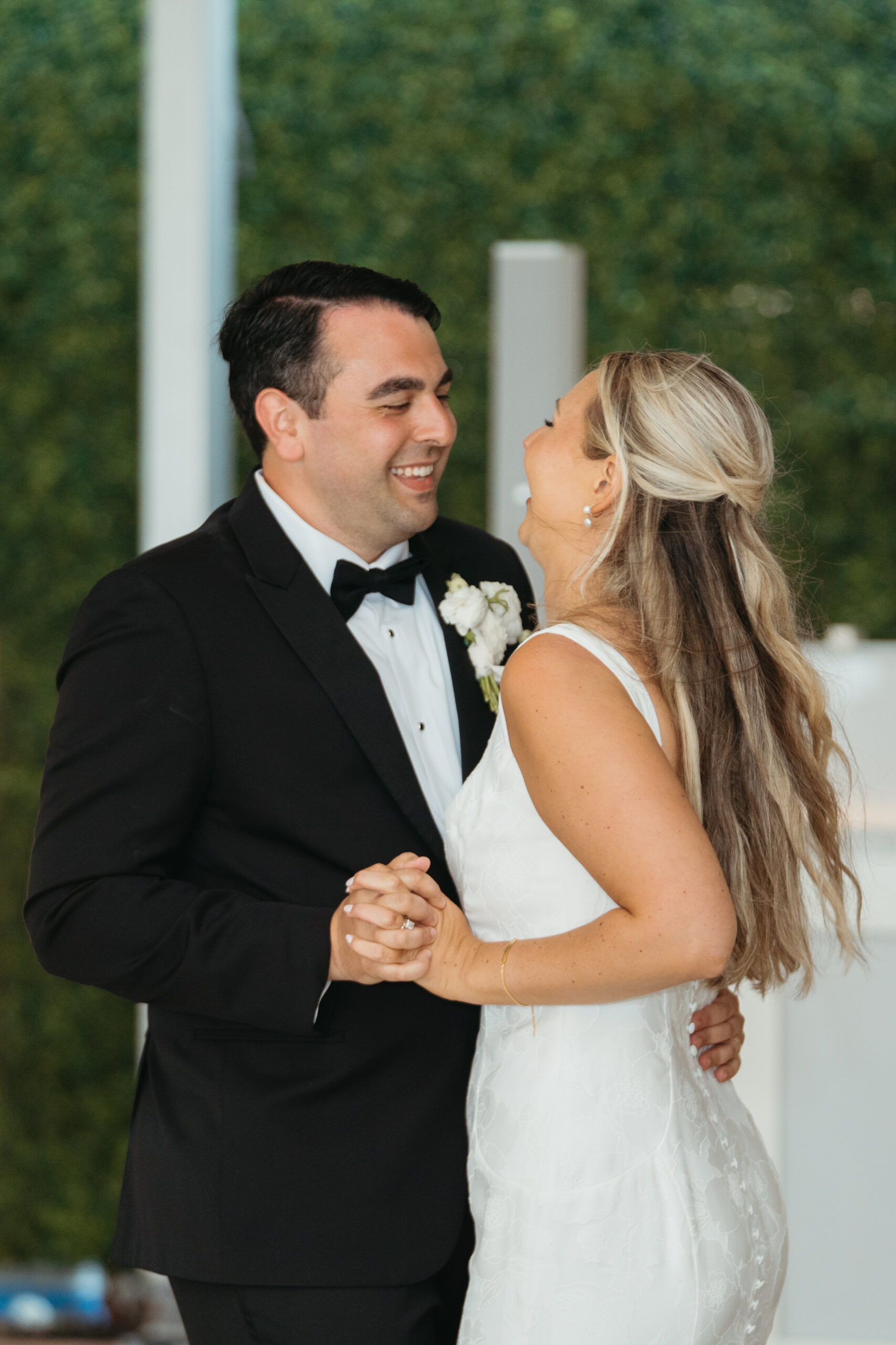 Bride and groom sharing their first dance, smiling and holding hands during the reception.