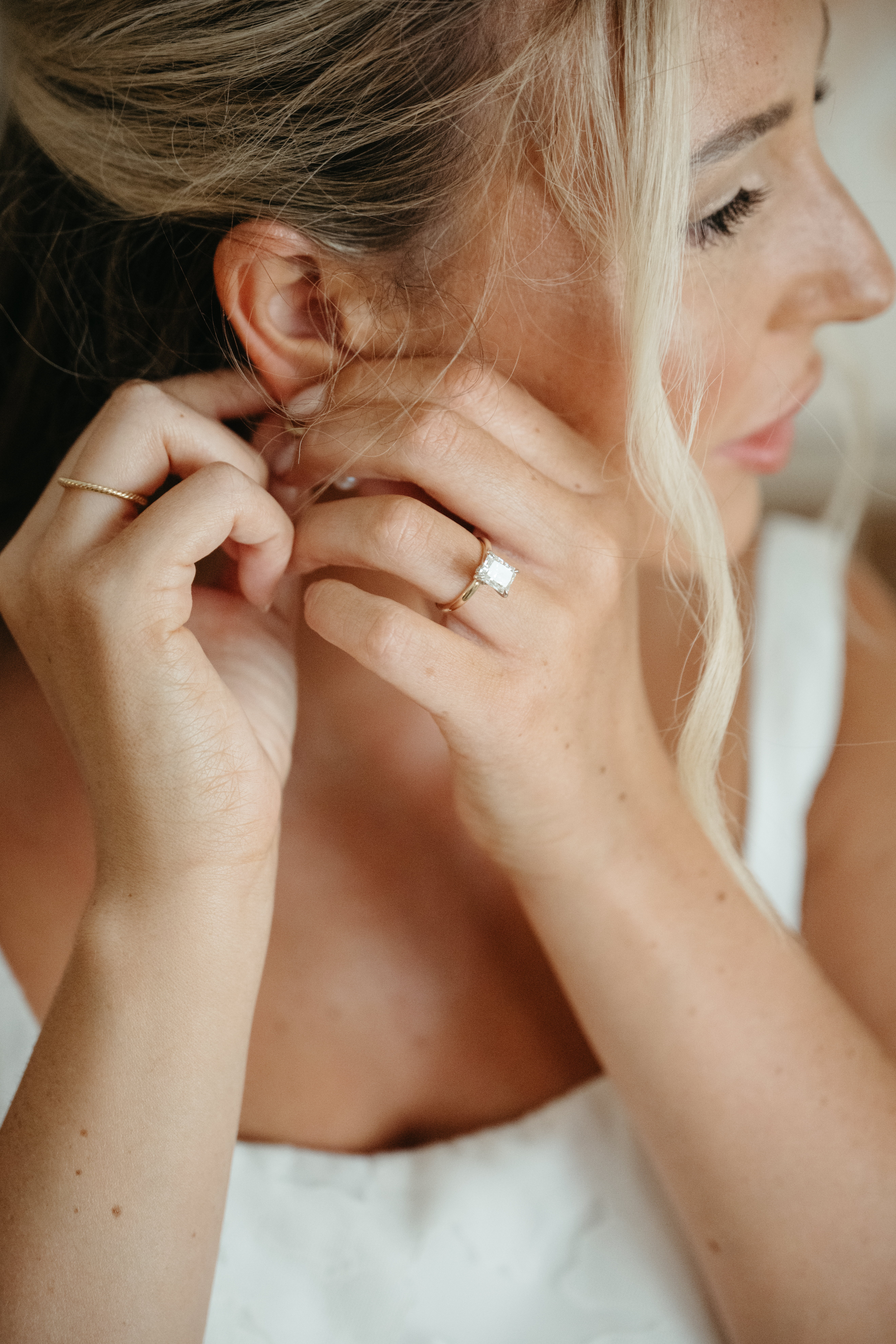 Close-up of the bride adjusting her earrings while getting ready for her Georgia wedding, showing her emerald-cut engagement ring and soft bridal makeup.