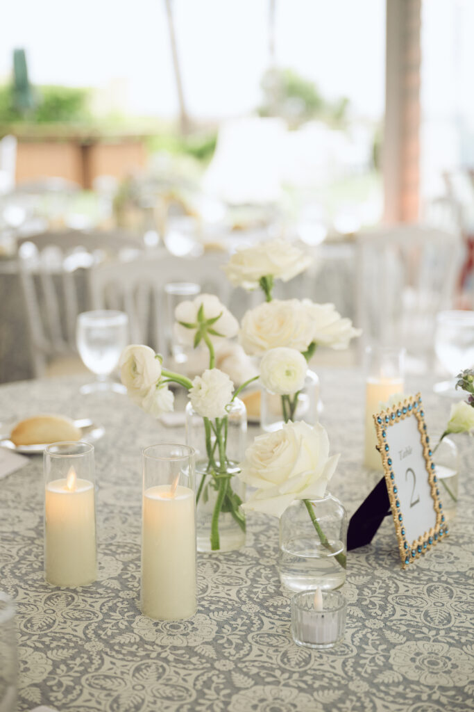 Romantic reception table with white florals, candles, and a beaded table number sign