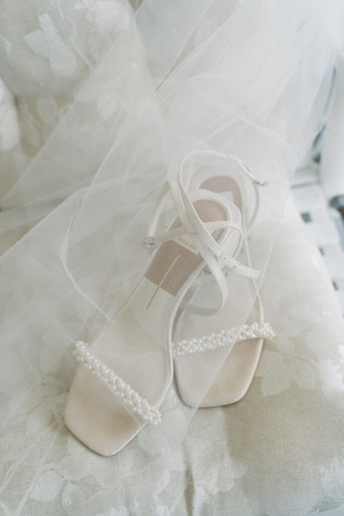 Close-up of elegant pearl-trimmed bridal heels under a delicate veil, captured during a Georgia wedding at The King and Prince Resort.