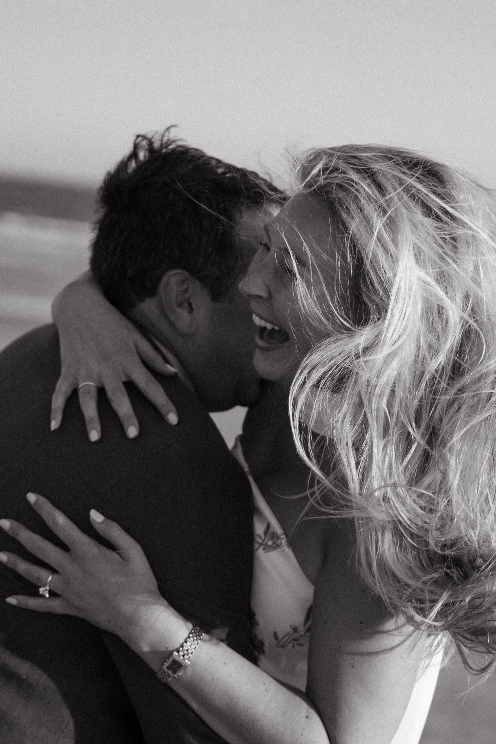 Black and white close-up of a bride laughing with the groom during their Georgia wedding, her hair windswept and arms wrapped around him.
