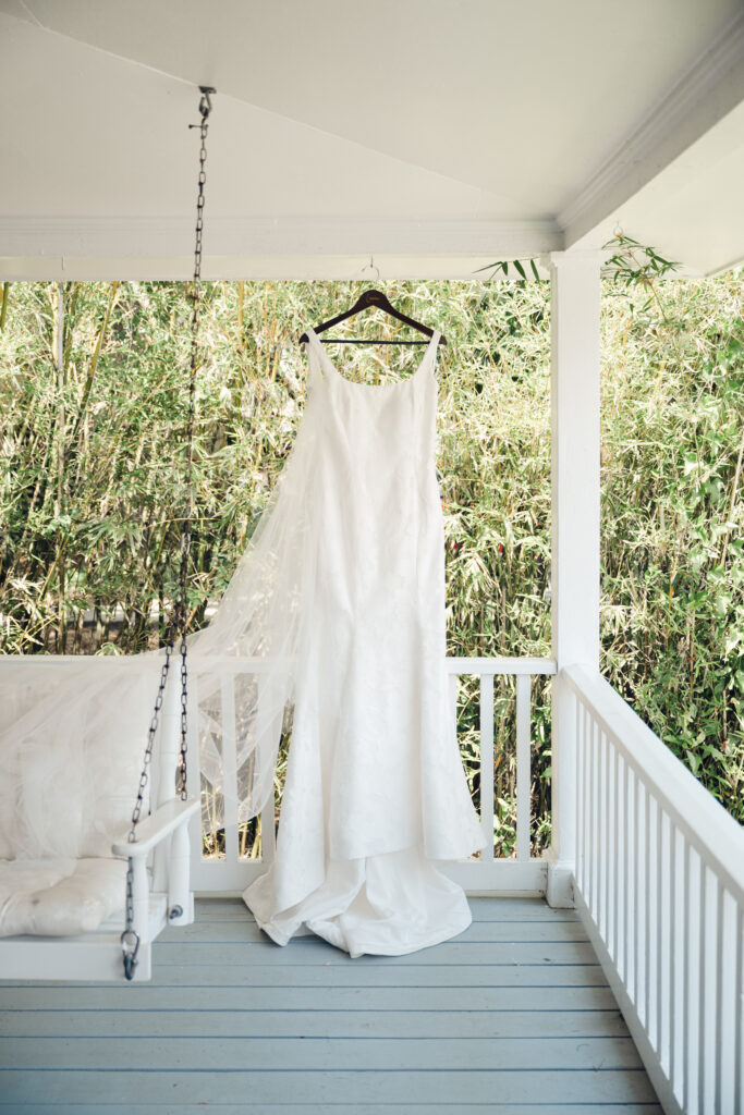 Elegant white wedding dress hanging on a porch at The King and Prince Resort, ready for a Georgia wedding celebration.