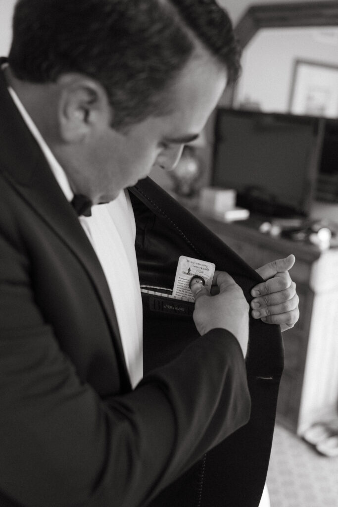The groom tucks a sentimental card from his mom into the inside pocket of his suit jacket before the wedding ceremony.