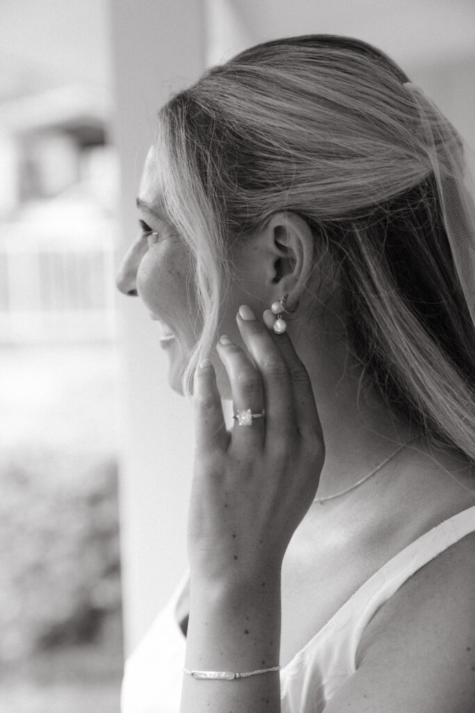Close-up of a bride smiling softly while adjusting her pearl earrings, captured on the morning of her Georgia wedding.
