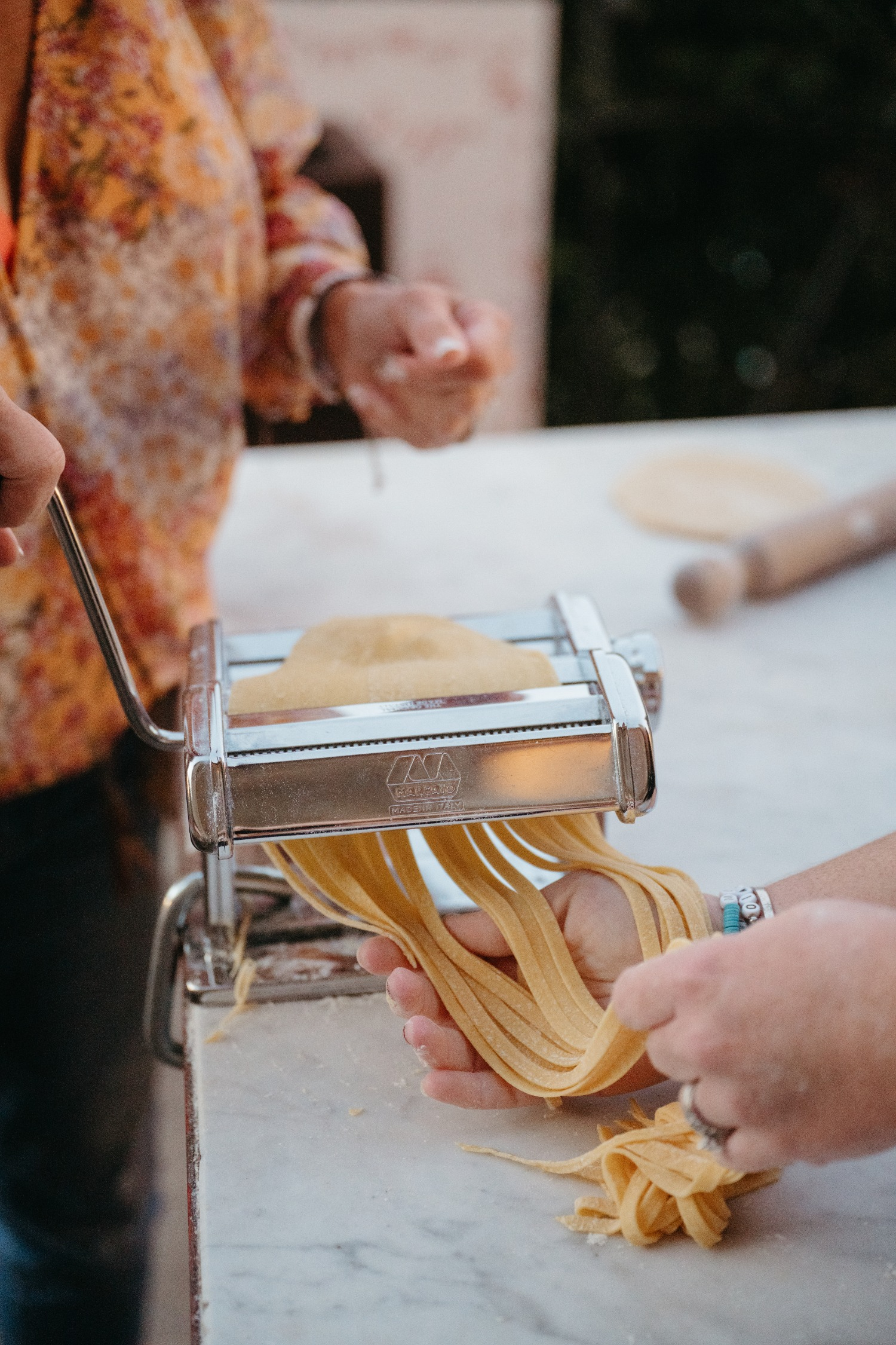 Close-up of fresh pasta being made by hand with a traditional machine — a meaningful cultural experience for couples getting married in Italy.
